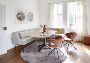 Ovaler Esstisch aus Holz mit Eckbank in beige und orangenen Lederstühlen