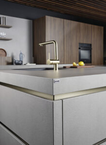 Nahaufnahme einer grauen Kücheninsel mit modernem Wasserhahn in gold