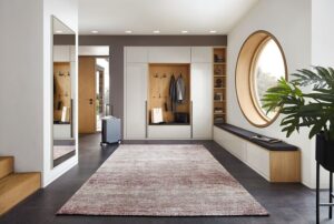 Heller Vorraum mit Bullauge und schöner Garderobe in weiß und Holz-Rückwand