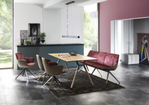 Esszimmer mit Holztisch und Sitzgruppe mit rotem Samtbezug auf der Sitzfläche