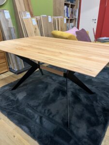 Esstisch aus hellem Holz mit schwarzen X-Beinen