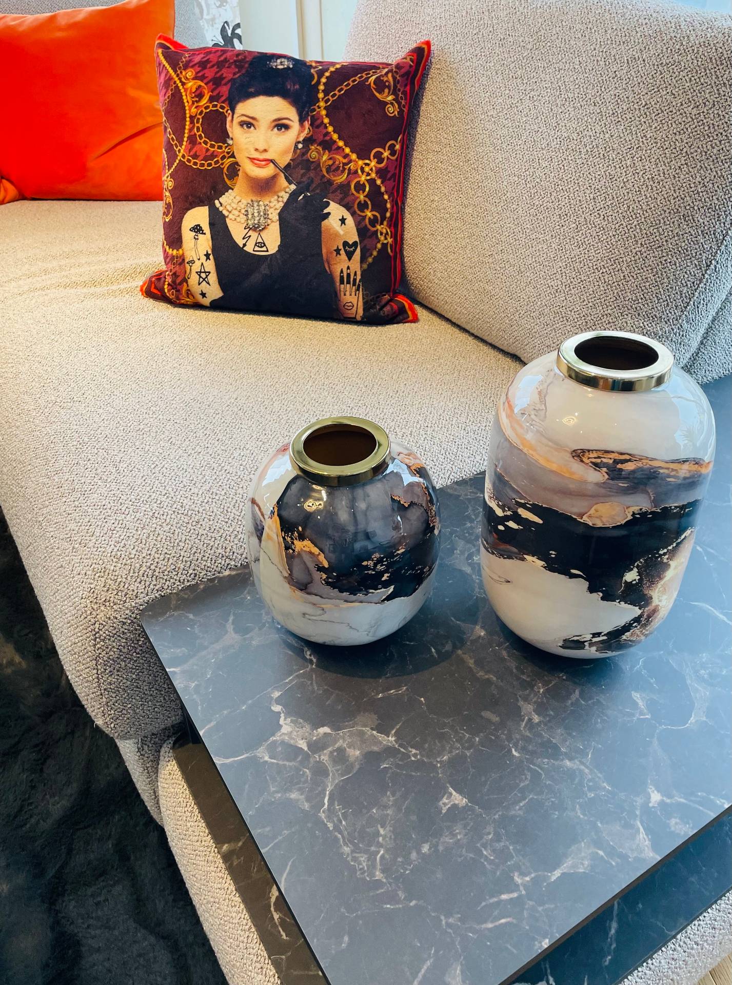 Wohntrends 2026: Marmorierter Beistelltisch mit Vasen vor grauer Couch und Motivkissen von Möbel Polt.