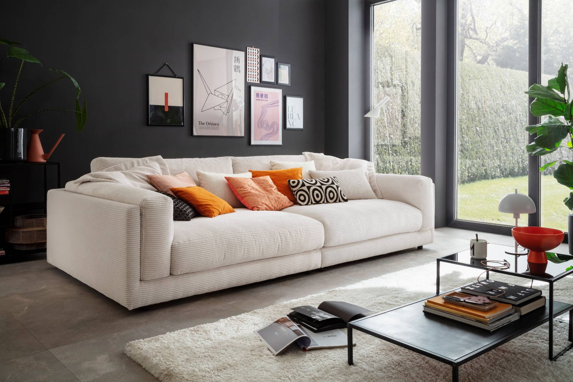 Modernes weißes Sofa mit Cordbezug vor dunkler Wand, dekoriert mit orangefarbenen Kissen für die Wohntrends 2026.