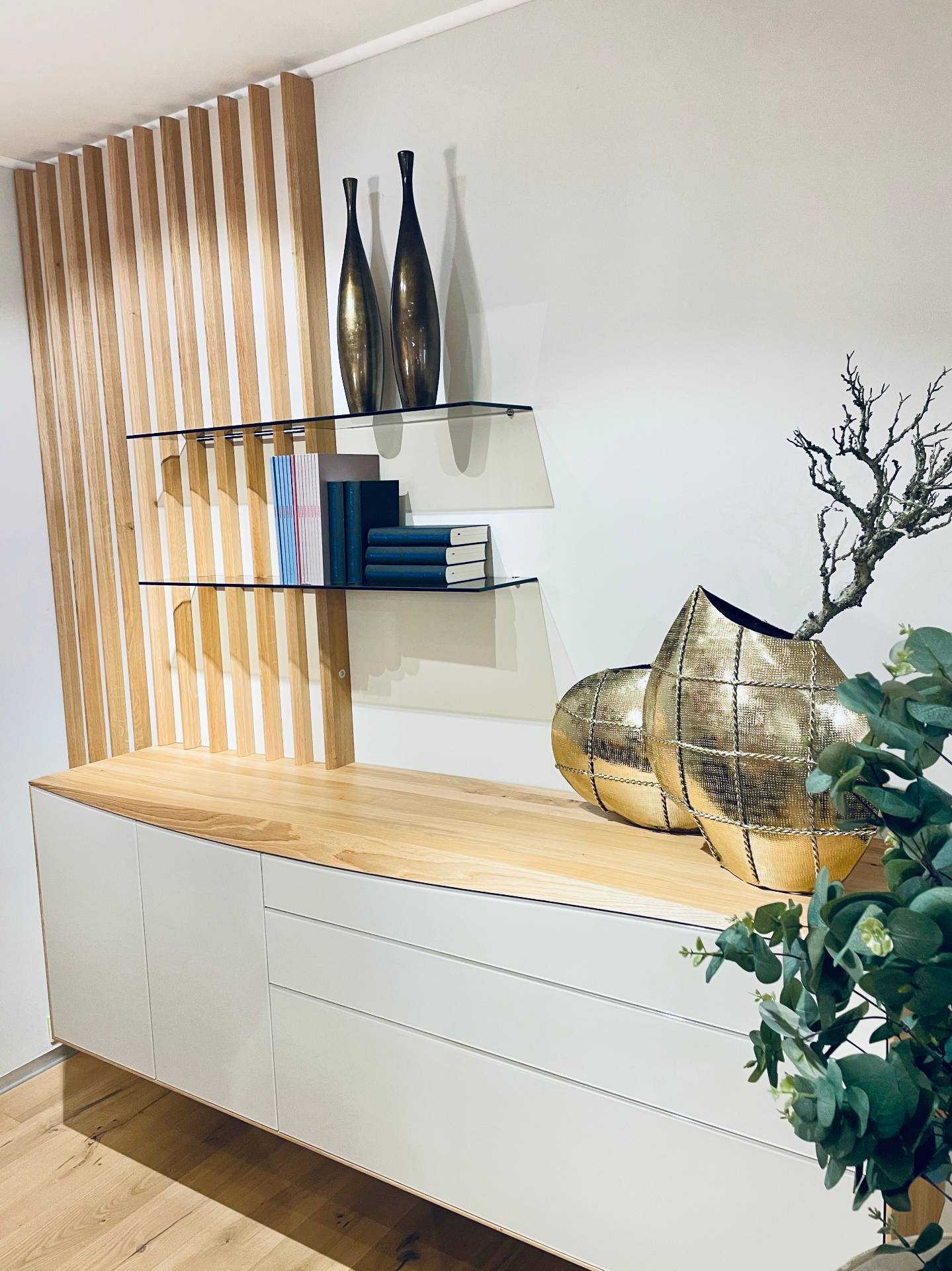 Möbel Polt Wohntrends 2026: Modernes Vorraum-Sideboard in Weiß und Eiche mit Glasregalen und goldenen Vasen.