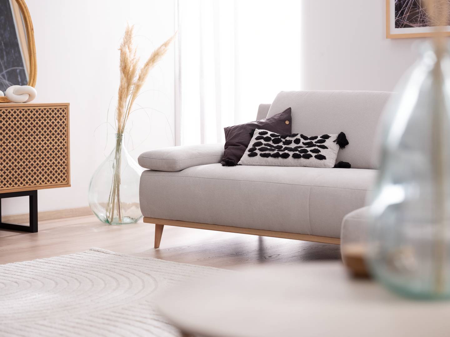 Modernes hellgraues Sofa in L-Form mit Holzfüßen, Dekokissen und Wohntrends 2026 im hellen Wohnzimmer von Möbel Polt.