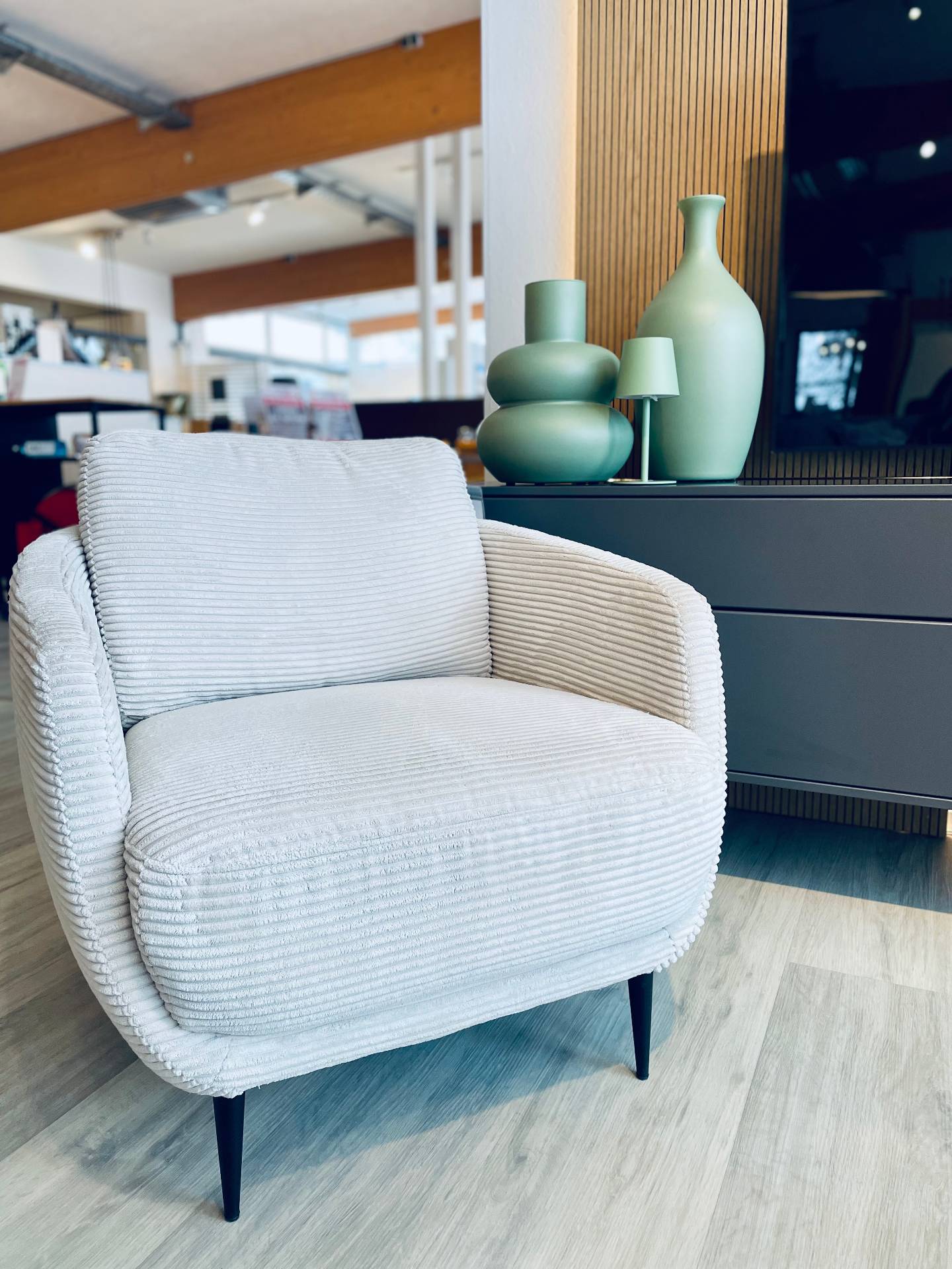 Moderner Wohnzimmer-Sessel mit hellem Cord-Stoffbezug vor grüner Deko; Wohntrends 2026 bei Möbel Polt präsentiert.